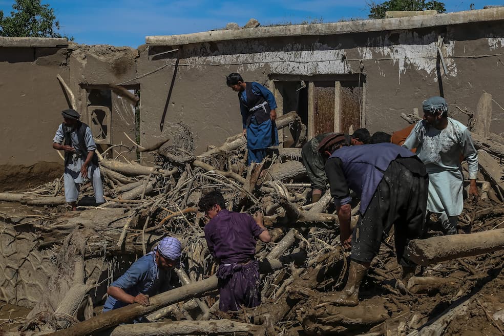 Mannen zoeken naar slachtoffers in de verwoeste huizen na de plotselinge overstromingen in het dorp Borka in de noordelijke provincie Baghlan van Afghanistan, 13 mei 2024