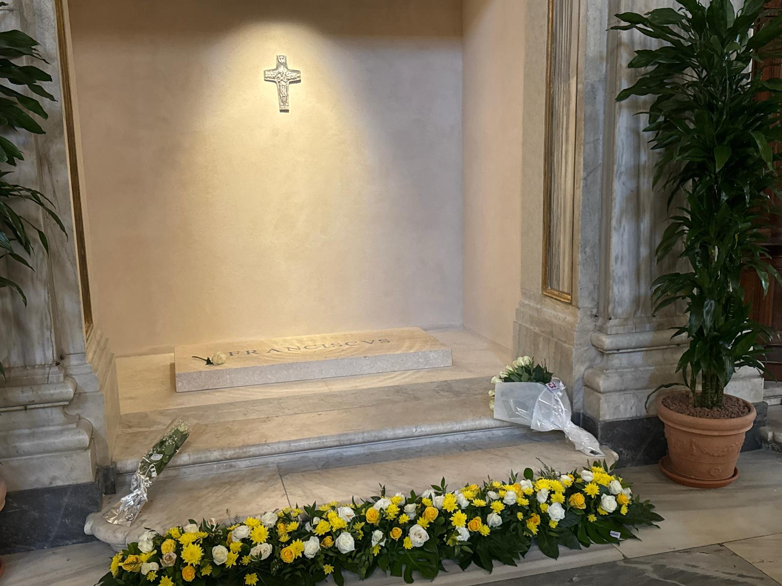 Het graf van Franciscus, een witte roos naast de naam, mooi verlicht met een kruisje erboven.