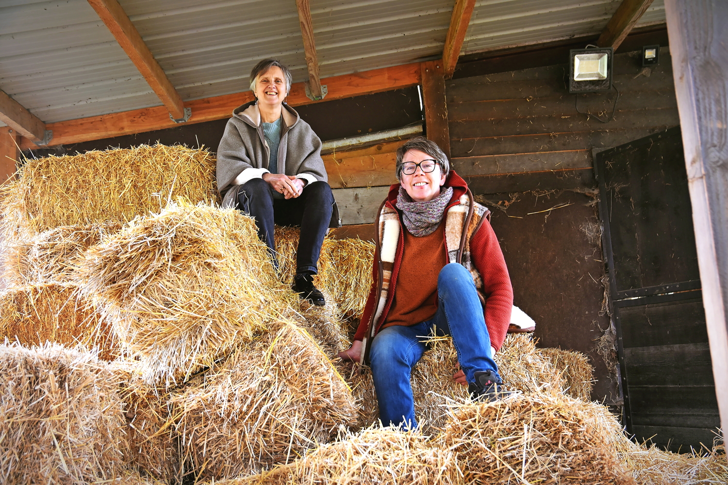Greet Herkes (links) en Katja Van Goethem op balen stro in hun zorgboerderij in Baal. © Tony Dupont