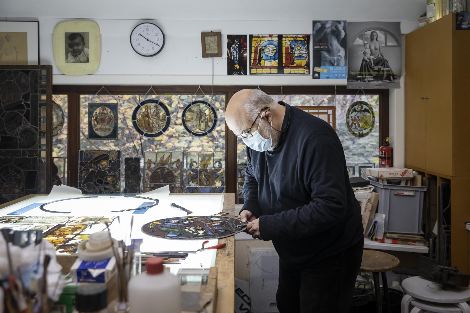 Joost Caen aan het werk in zijn atelier, een schatkamer die heel wat waardevolle glasramen onderdak biedt. 